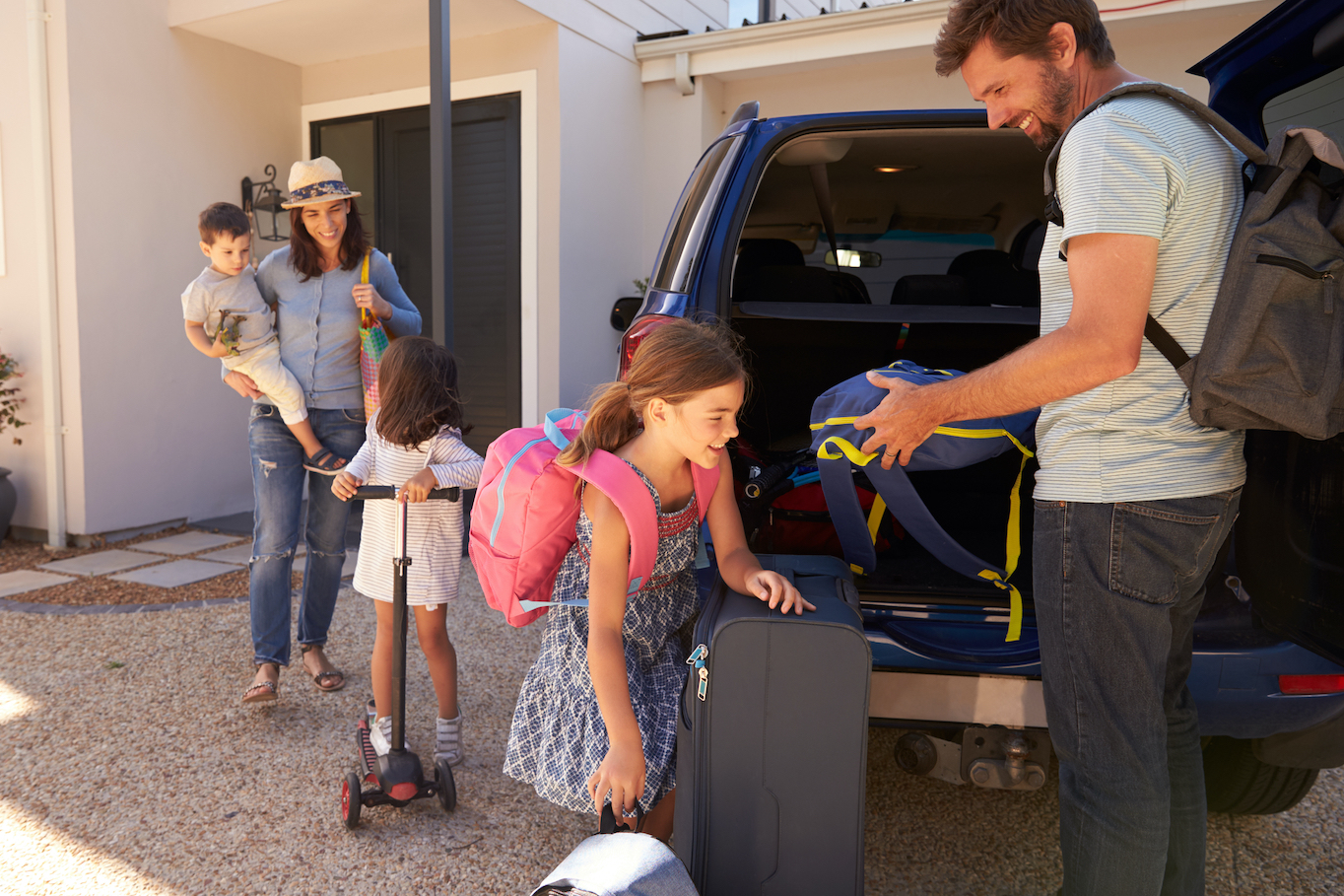 Couple with three children unpacking car trunk