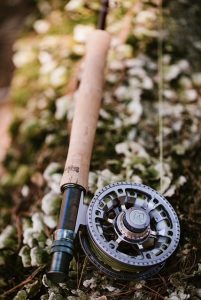 A Maine Fly Company fly-fishing reel laying on moss