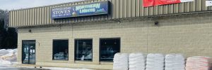 Northern Lights Hearth and Sports Store front with signage and pallets of goods, on a sunny day with some residual snow is on the ground