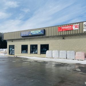 Northern Lights Hearth and Sports Store front with signage and pallets of goods, on a sunny day with some residual snow is on the ground