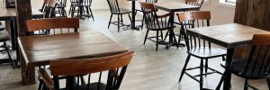 Photo of the dining room at CIA Cafe, wooden tables and chairs and windows letting in natural light on the neutral walls and floor.