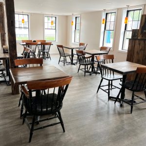 Photo of the dining room at CIA Cafe, wooden tables and chairs and windows letting in natural light on the neutral walls and floor.