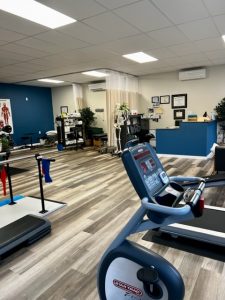 Entrance to a physical therapy practice, includes comfortable looking chairs and medical equipment