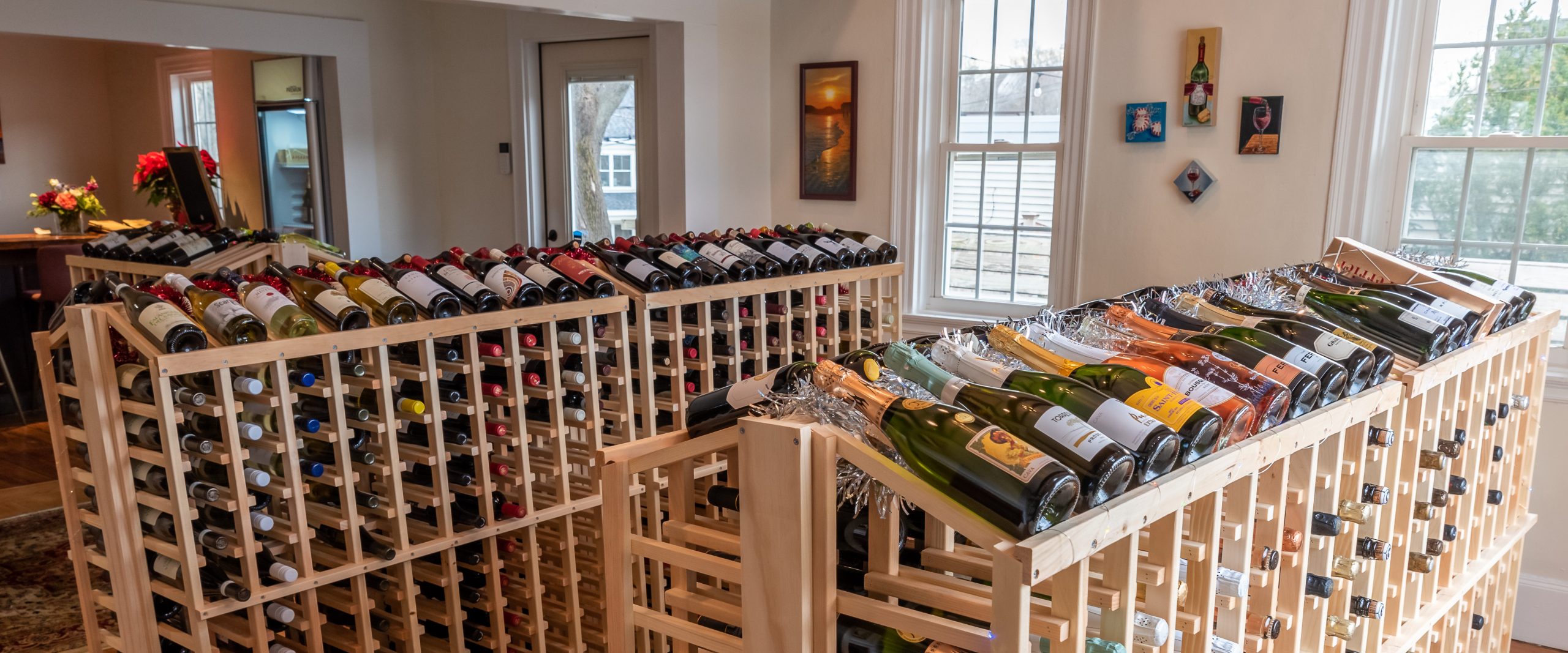 Photo of the inside of Wine House on Main shop showing wine display, widows and small wall art. 