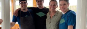 Group Photo of The Osprey Resturant, two white men and two white women with their arms around each other inside a restaurant doorway.