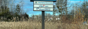 Gray Urgent Care sign amongst tall grasses