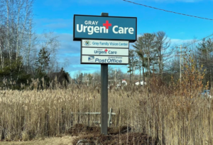 Gray Urgent Care sign amongst tall grasses