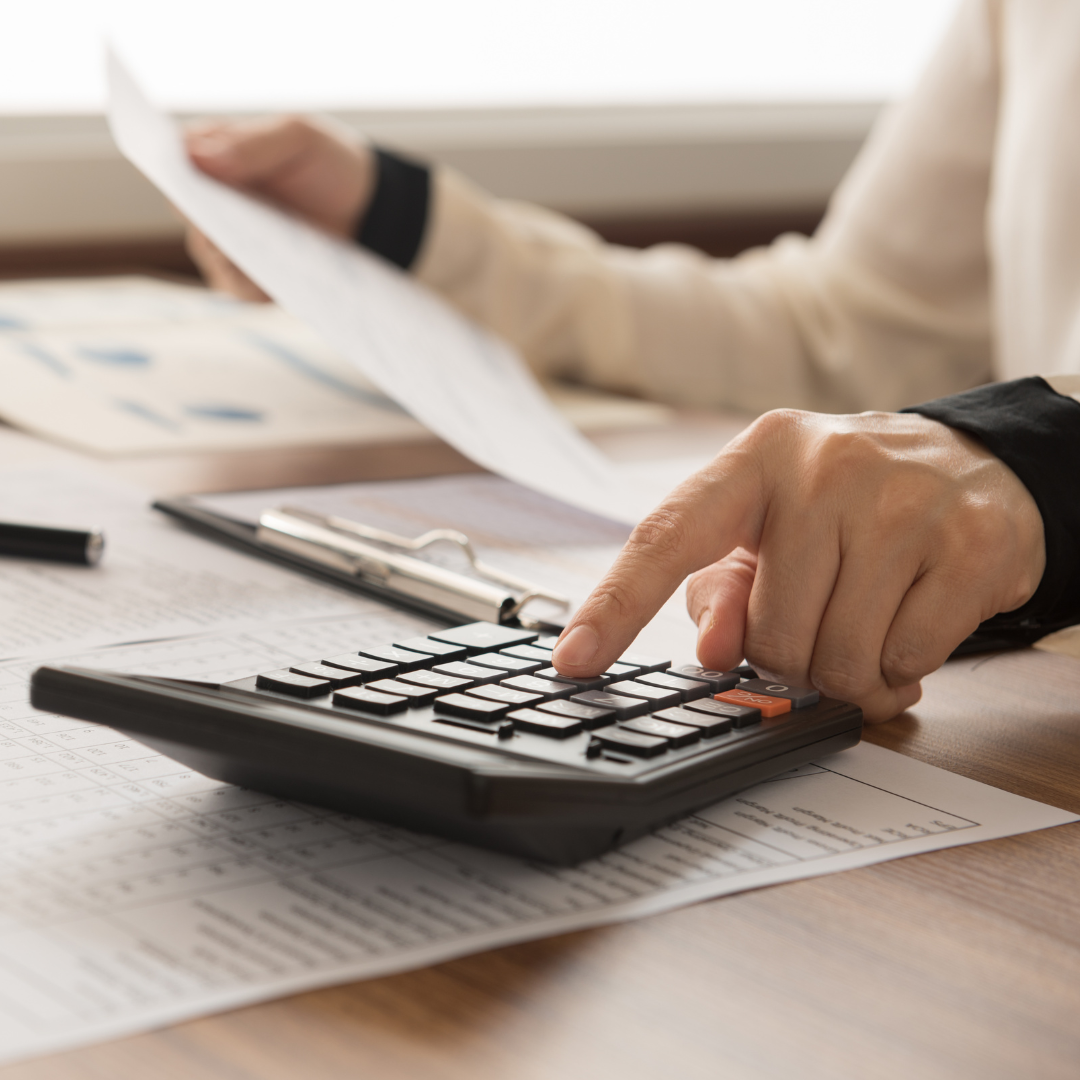 Hands holding accounting paperwork and using a calculator