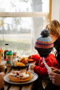Small child wearing a knit hat getting ready to eat a waffled at a Maine Small Business, photo by Sienna Renee Photography