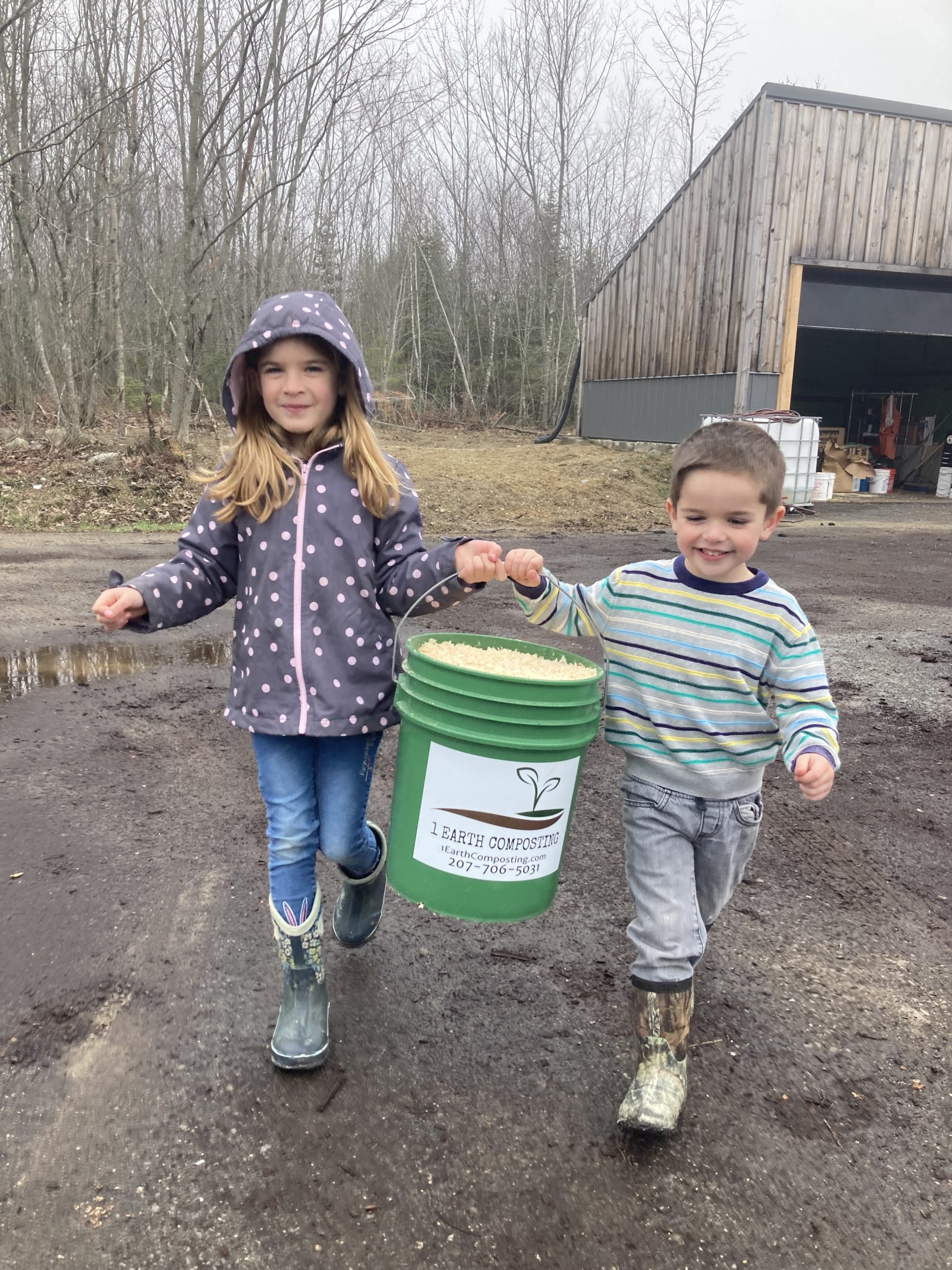 Saunders children helping carry compost bucket for 1 Earth Composting