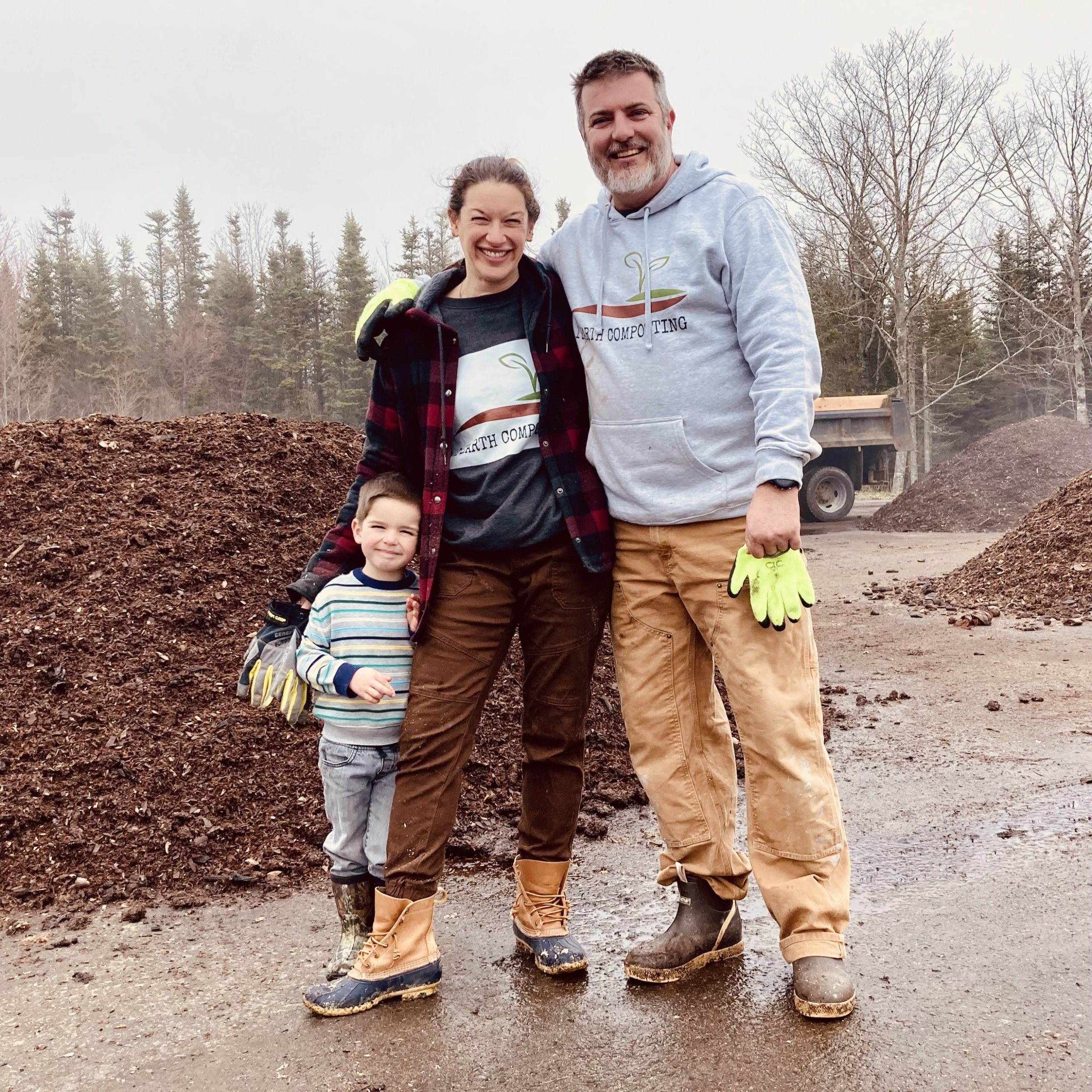 Katie and Matt Saunders stand with their young on in front of compost pile