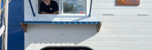 White food truck with man inside smiling, Great Wave Sushi food struck with flowers