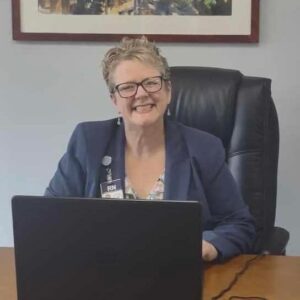Heather Fogg, business owner of Fundamental Footcare, sitting behind a computer, smiling