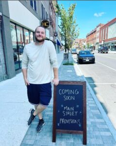 Zach Brann, owner of Main Street Provisions, outside of his business with a "Coming Soon" sign