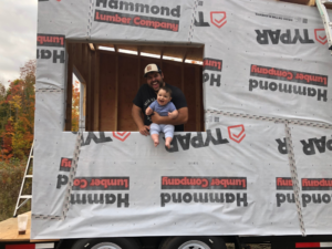 Alex Herzog with baby in food truck with tyvek, in the middle of construction as he grows his business