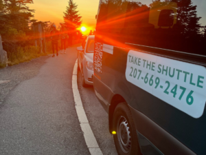 Cadillac Mountain Summit Shuttle van with phone number on side at sunset