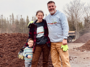 Matt and Katie Saunders with young son smiling at their composting business, 1 Earth Composting